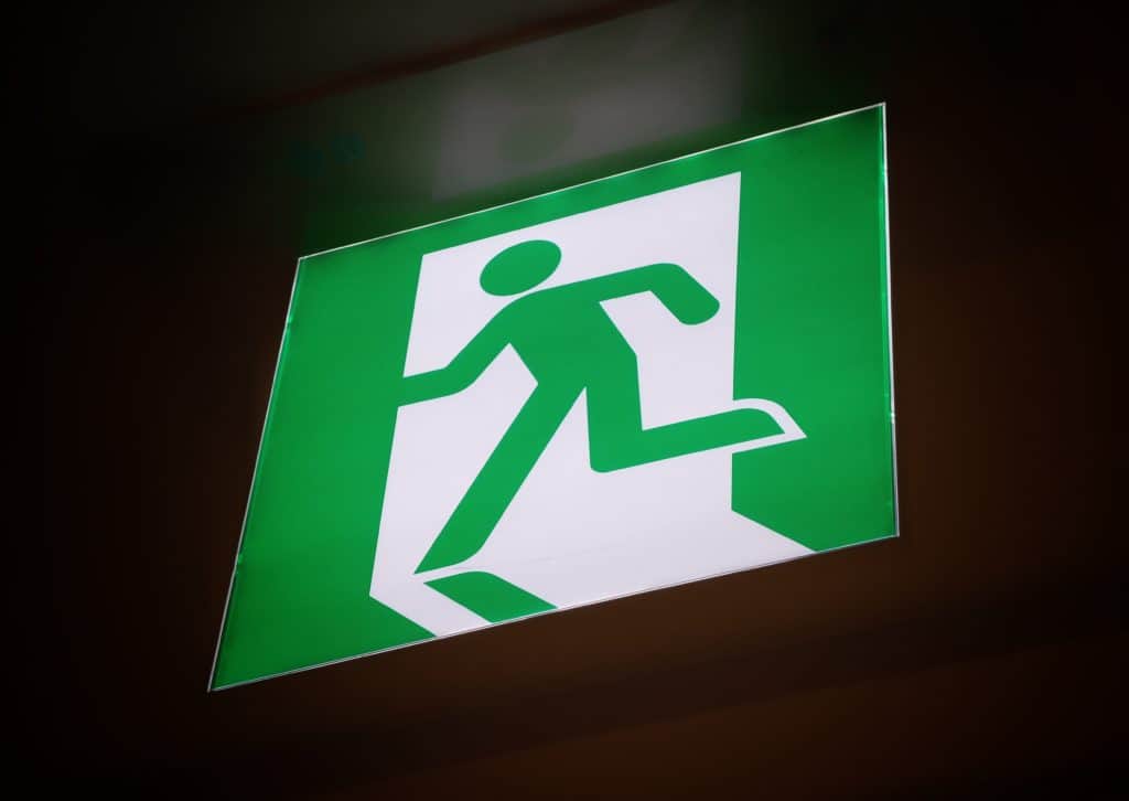 A green and white sign, which shows a green stick figure running out a white doorway.  