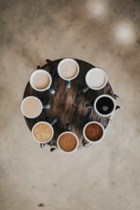 8 coffee cups in a circle of varyng shades - darkest and lightest are around 3 o'clock, with the shades moving clockwise