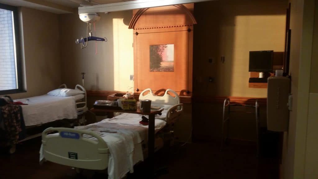 The sunlight shines into a generous hospital room.