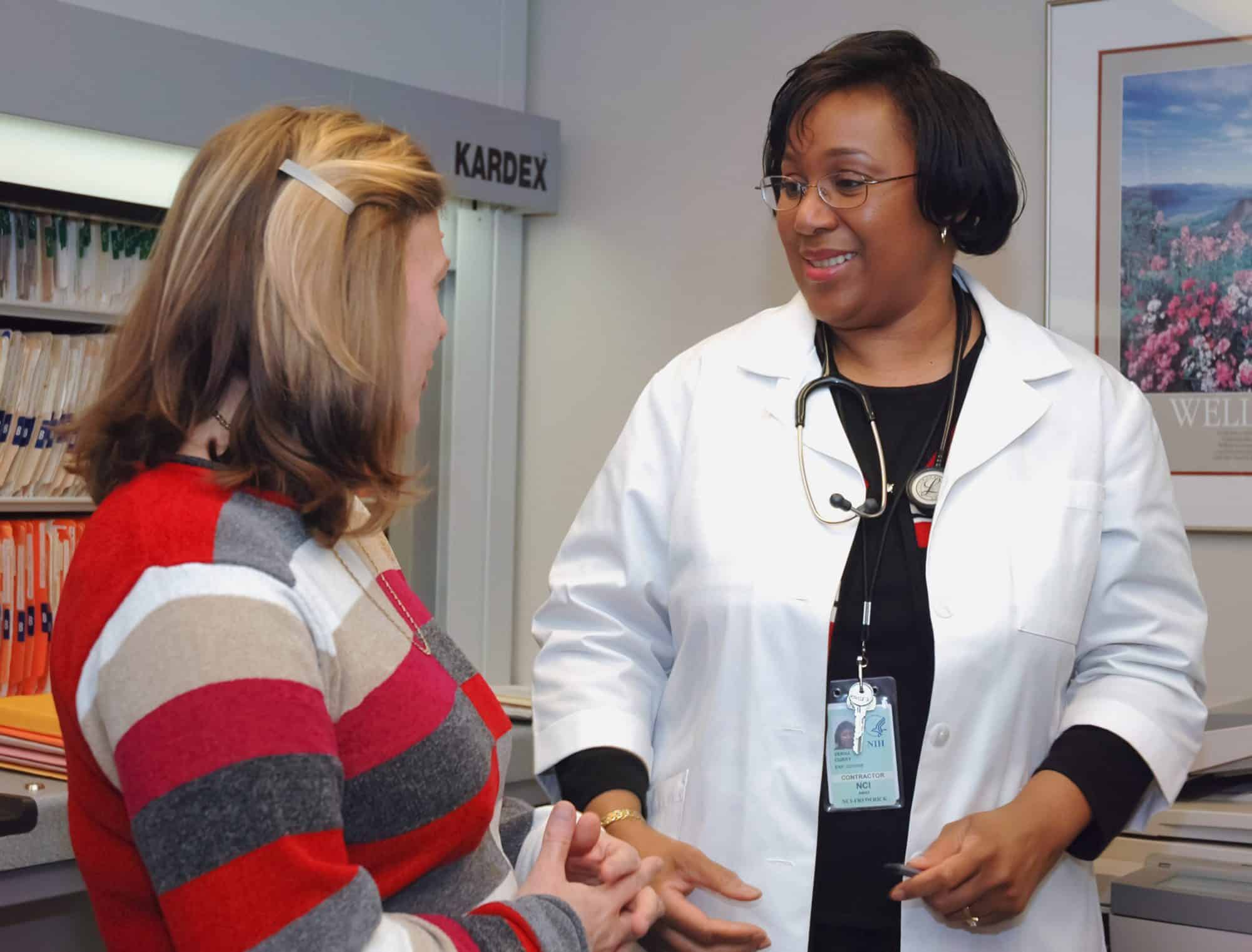 A black female doctor talks to her white female patient